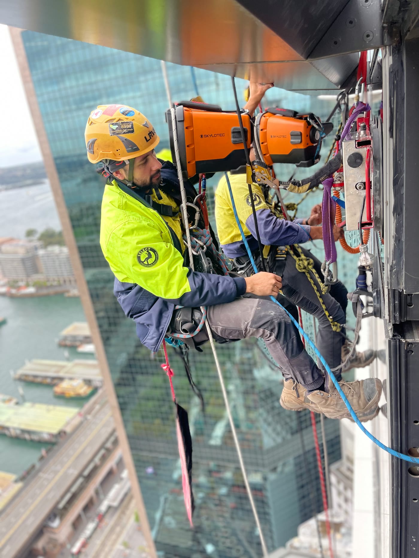 Technician working on glazing with harbour views